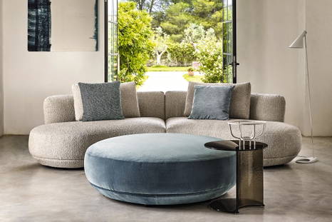 The Amalfi Armless Curved Sofa and pouf with the Berger occasional table