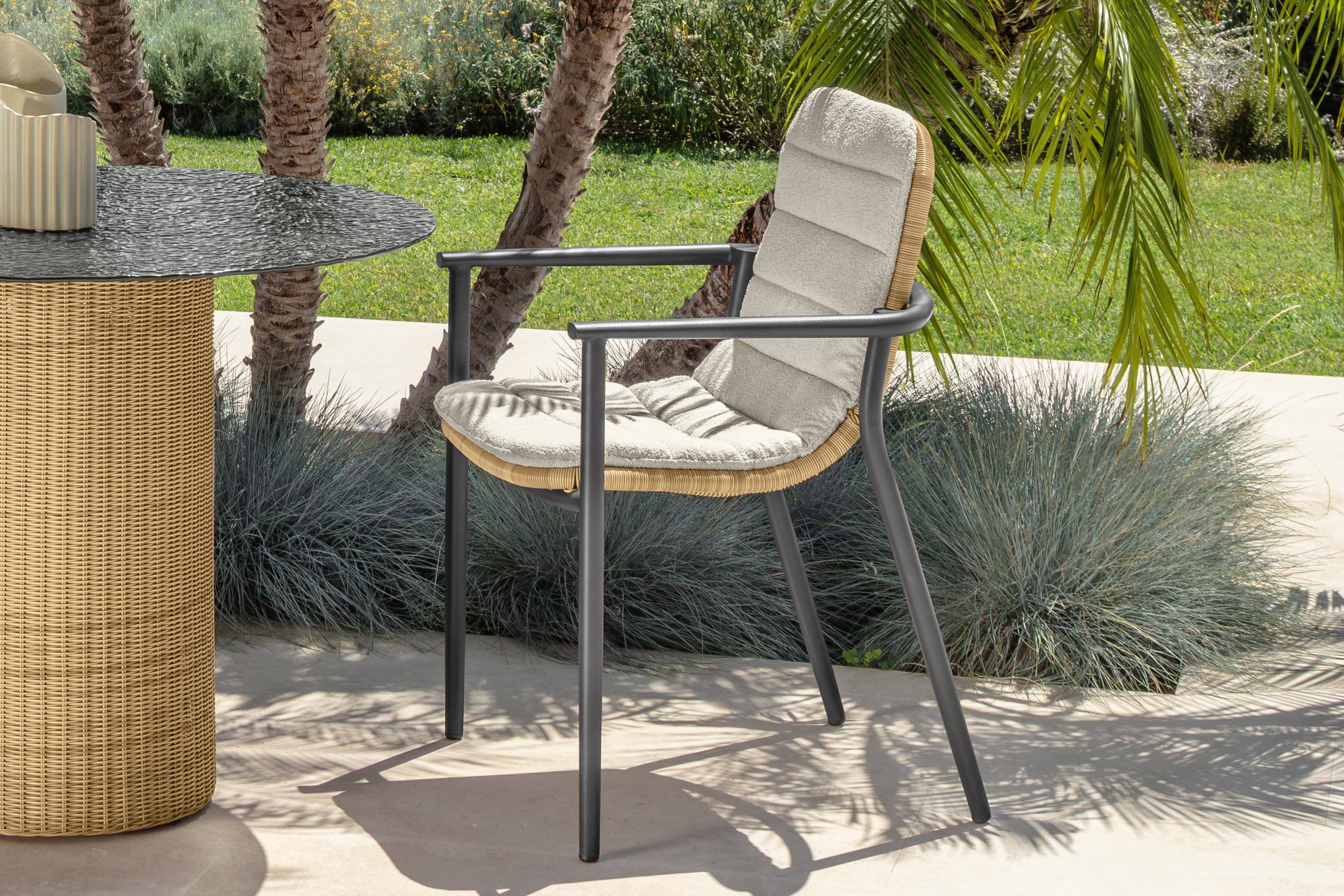 The Bond dining armchair with a beige wicker back and seat and graphite aluminium frame.